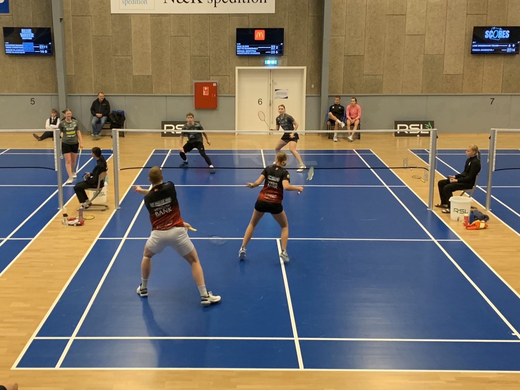 Mixdouble i Esbjerg med SCORES-skærme over banerne